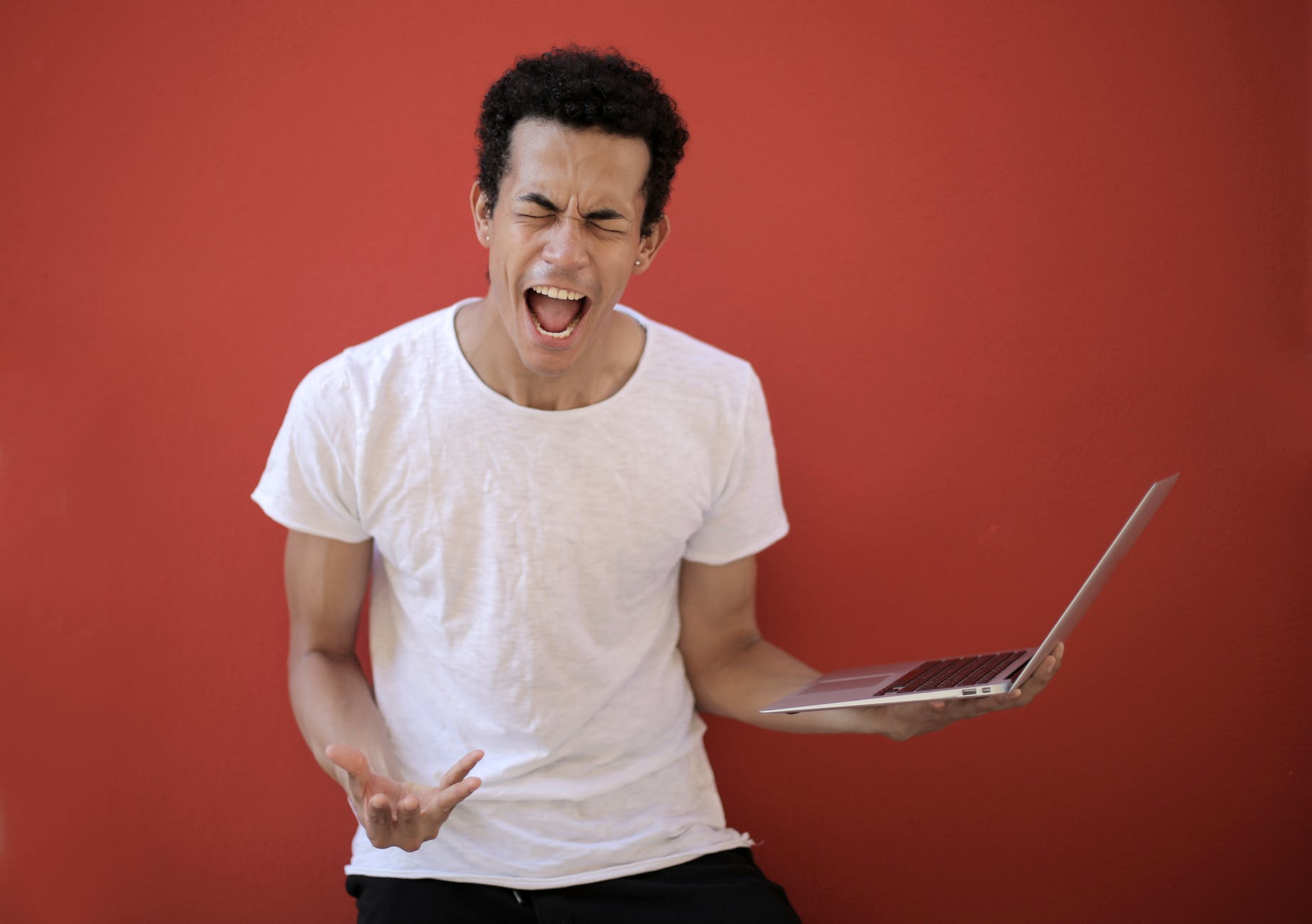 young ethnic male with laptop screaming
