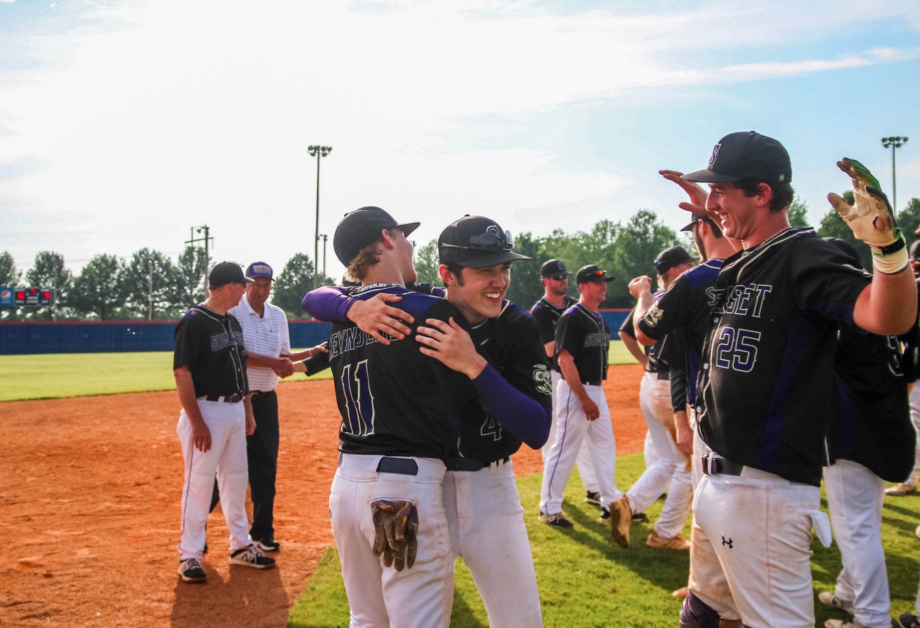 two men hugging each other on baseball field