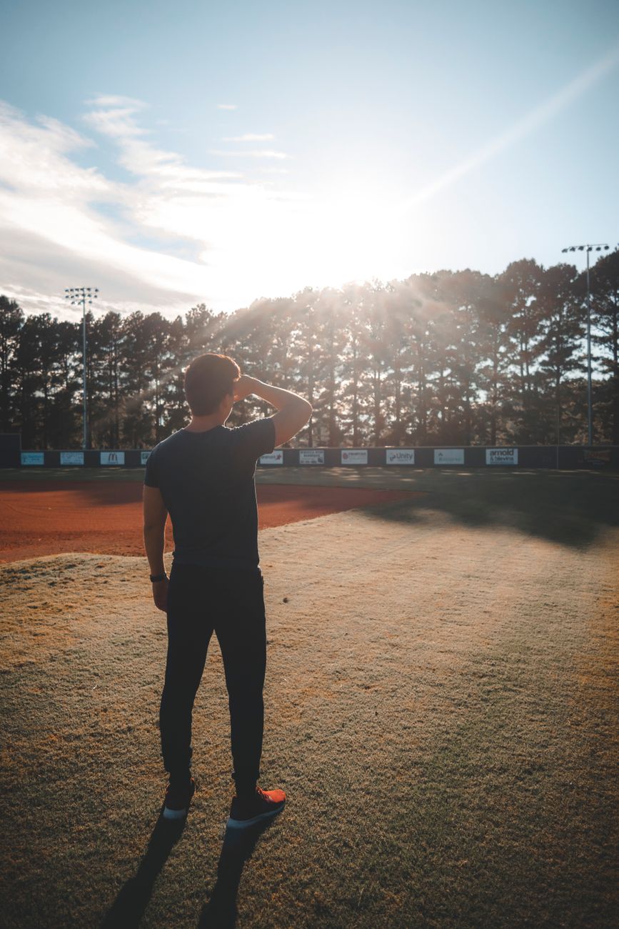 man standing on field looking on trees
